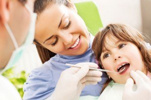 Dentist and assistant showing pediatric dental patient how to look after his teeth